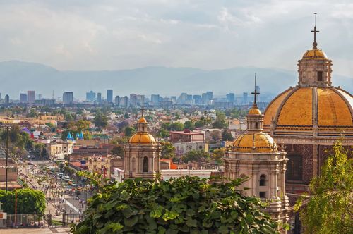 Old Basilica of Guadalupe with Mexico City skyline behind it