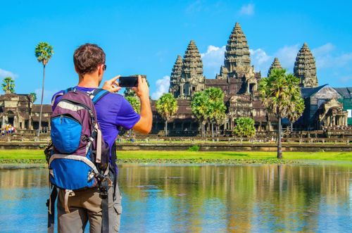 Young man is taking a photo of Angkor Wat temple, Siem Reap, Cambodia