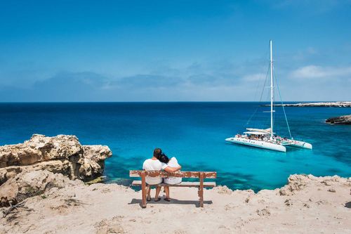 Loving couple sitting on a bench and looks at the lagoon